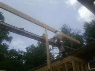 Carpenter setting a ridge beam over a new addition frame — Ice Dam Removal by Roofing Brothers in Holly Bluff