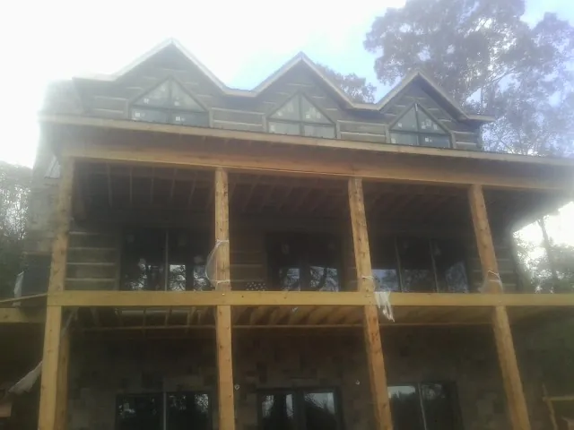 Dormers and porch framing on a large log home under construction — Roof Coating work by our crew in Holly Bluff