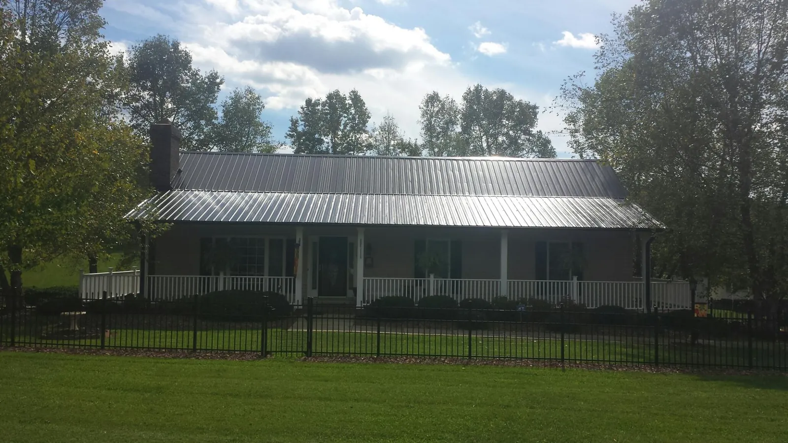 Gray metal roof on a brick ranch with a full width front porch — Gutter Guard Installation work by our crew in Holly Bluff
