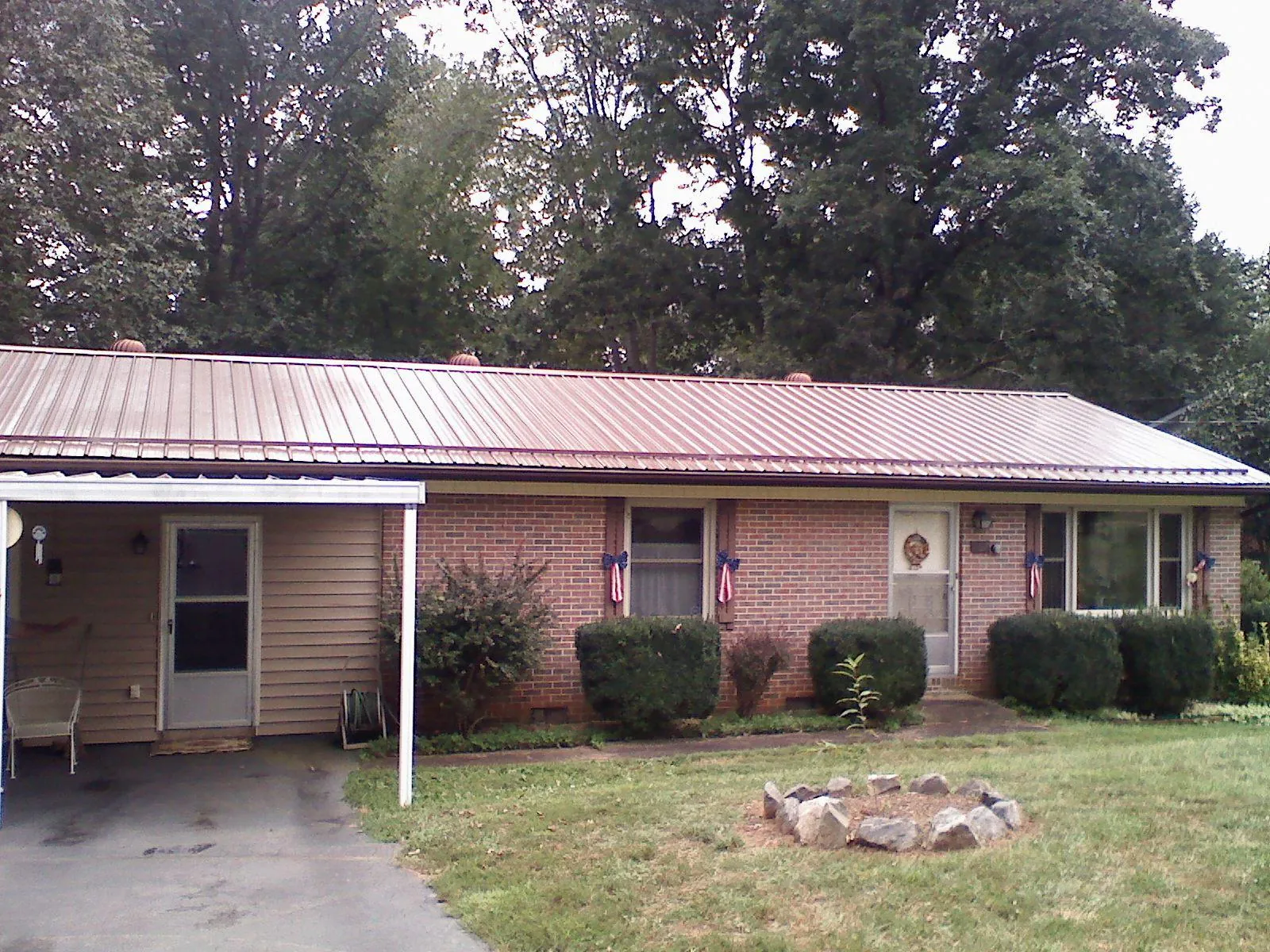 Bronze metal roof and carport on a brick ranch home — Roof Repair work by our crew in Holly Bluff