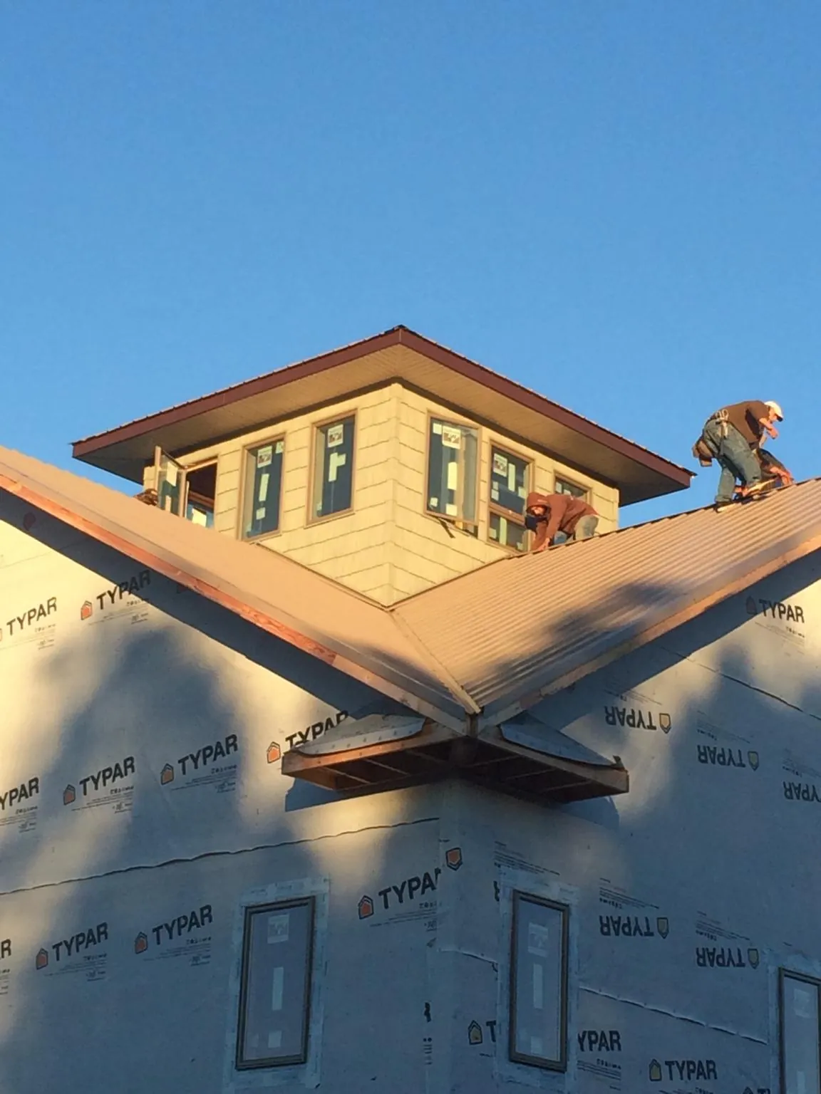 Roofers working around a rooftop cupola on a new metal roof at sunset — Roof Waterproofing in Holly Bluff by Roofing Brothers